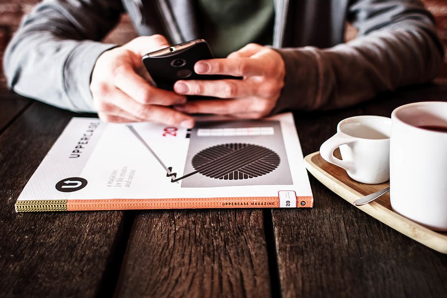person holding black Android smartphone while leaning on table HD wallpaper