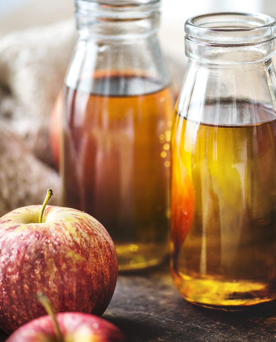Close-up Photography of Honeycrisp Apples and Two Clear Glass Bottles Filled With Liquid HD wallpaper