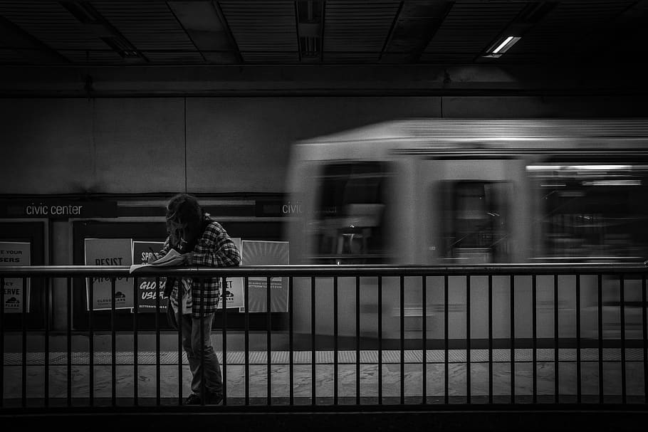 person standing inside train station behind train, railing, handrail HD wallpaper