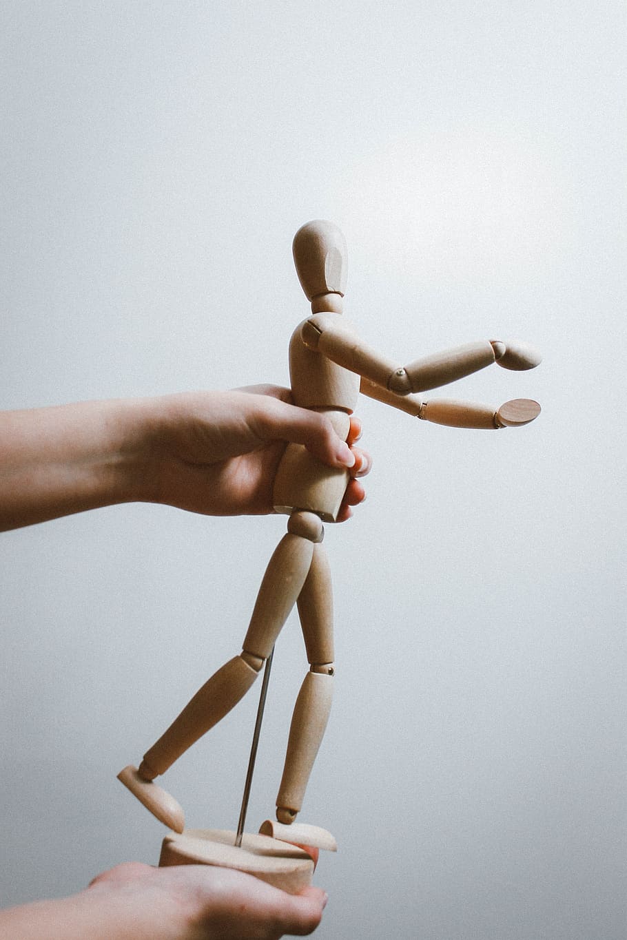 person holding brown artist mannequin, hand, conceptual, minimalism HD wallpaper