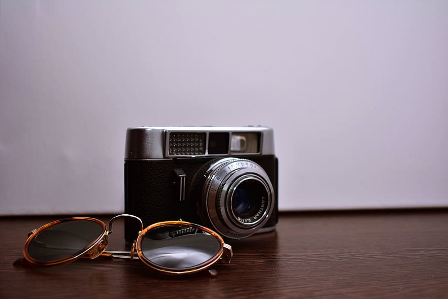 Silver and Black Dslr Camera With Brown Sunglasses on Brown Wooden Surface HD wallpaper
