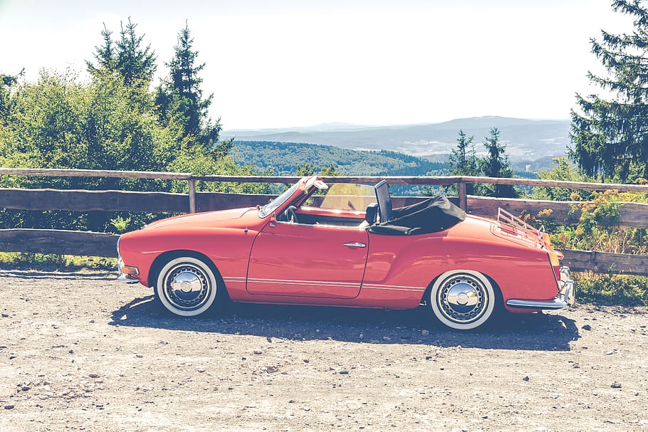 Red Convertible Coupe Parked Near Wooden Fence Overlooking Trees HD wallpaper