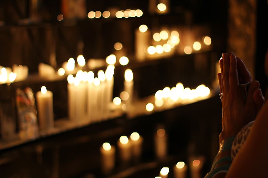 Close Up Photograph of Person Praying in Front Lined Candles HD wallpaper