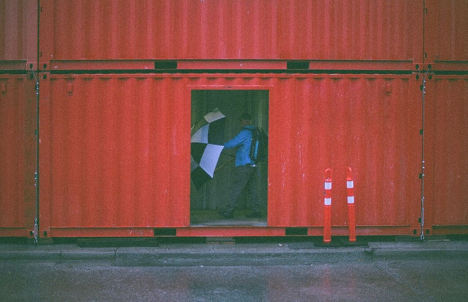 man holding umbrella inside the intermodal container, red, no people HD wallpaper