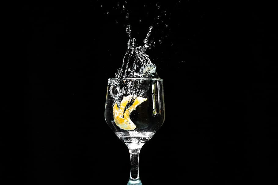Lemon in the Water Filled Wine Glass, black background, close-up
