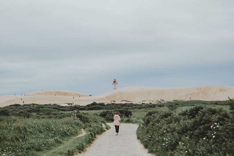woman walking beside green grasses during daytime, lighthouse HD wallpaper