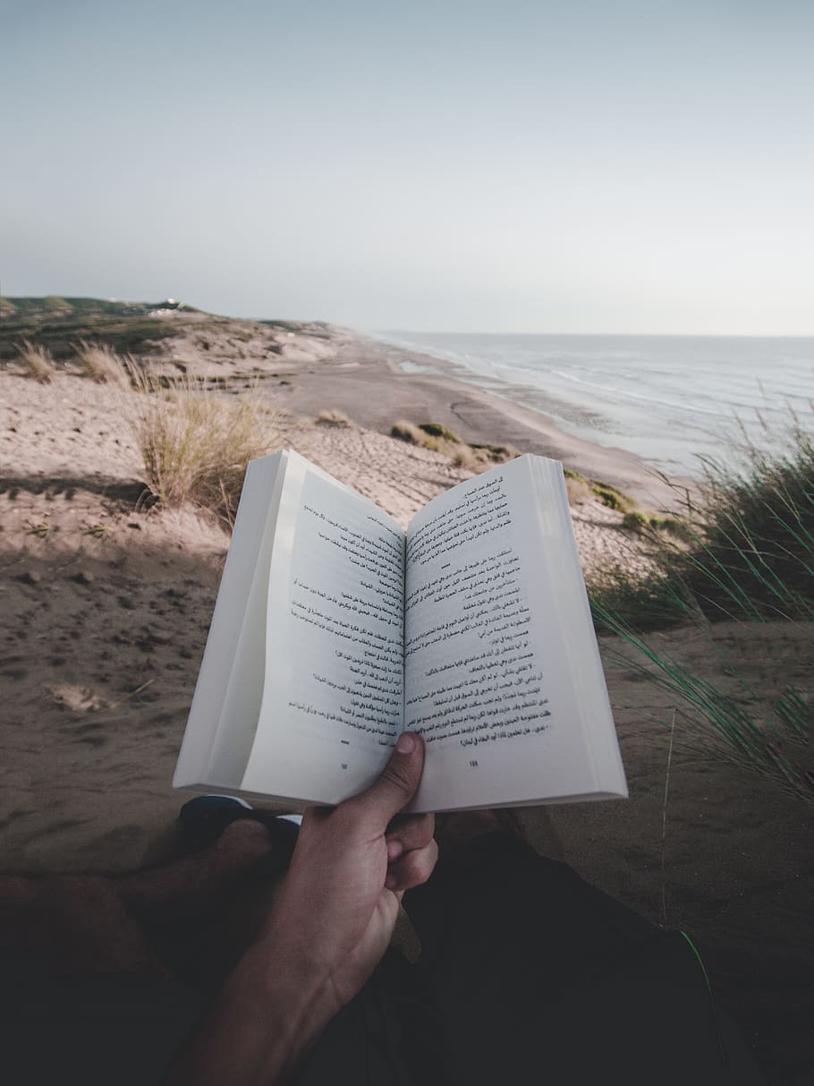 Photo of Person Reading Book On Beach, hand, idyllic, leisure HD wallpaper