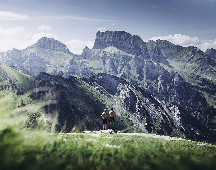 two men standing on rock during daytime, mountain, outdoors, mountain range