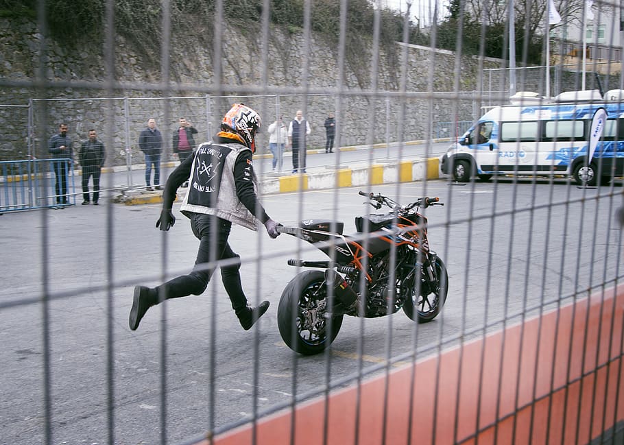 Man Holding Orange and Black Sports Bike on Asphalt Road, action HD wallpaper