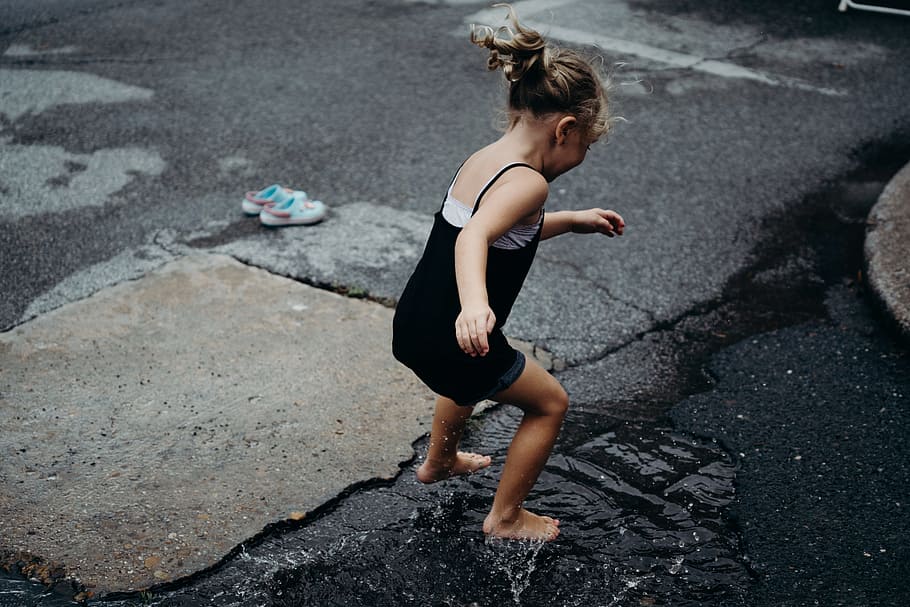 girl jumps in the water surface on asphalt road during daytime, HD wallpaper