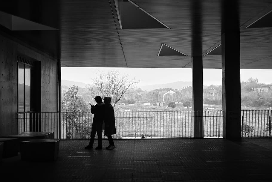 two people standing beside railings near door during daytime