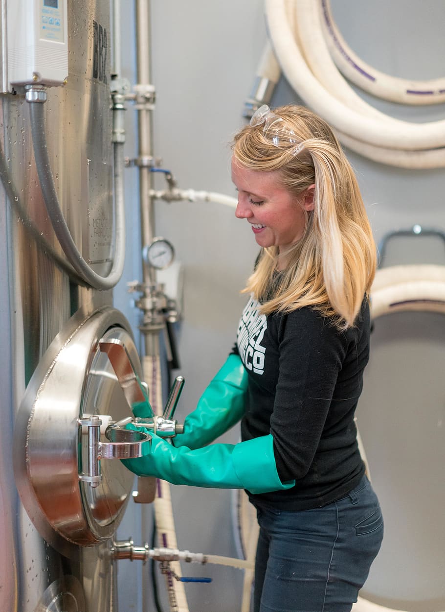 Woman in Black Shirt and Green Latex Gloves, blond hair, brewery