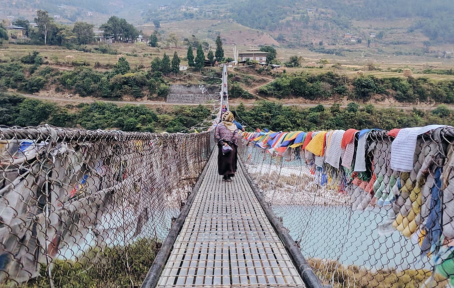 person walking on bridge with clothes hanging, building, suspension bridge