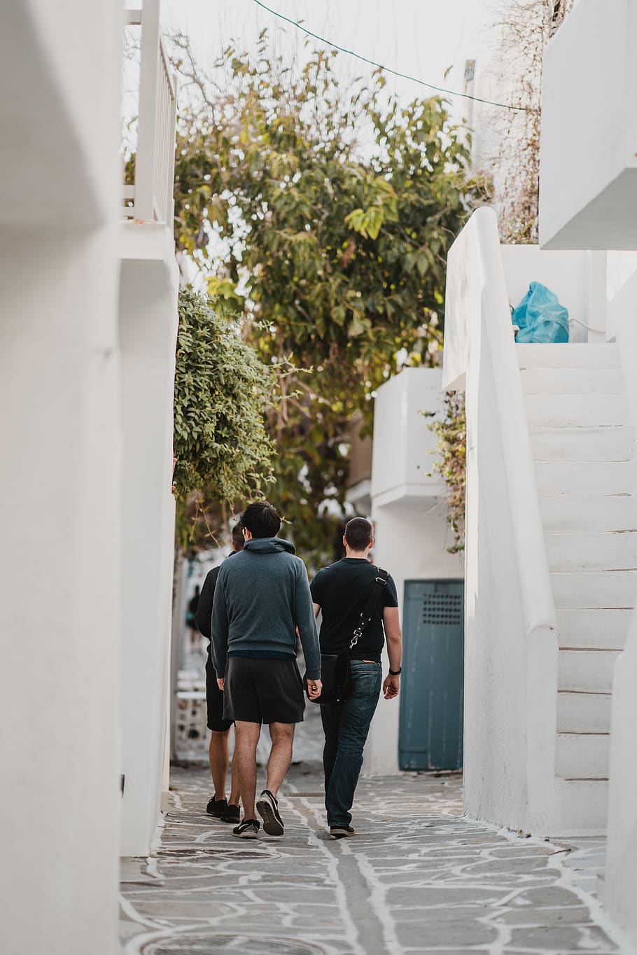 three men walking along narrow pathway between buildings, people HD wallpaper