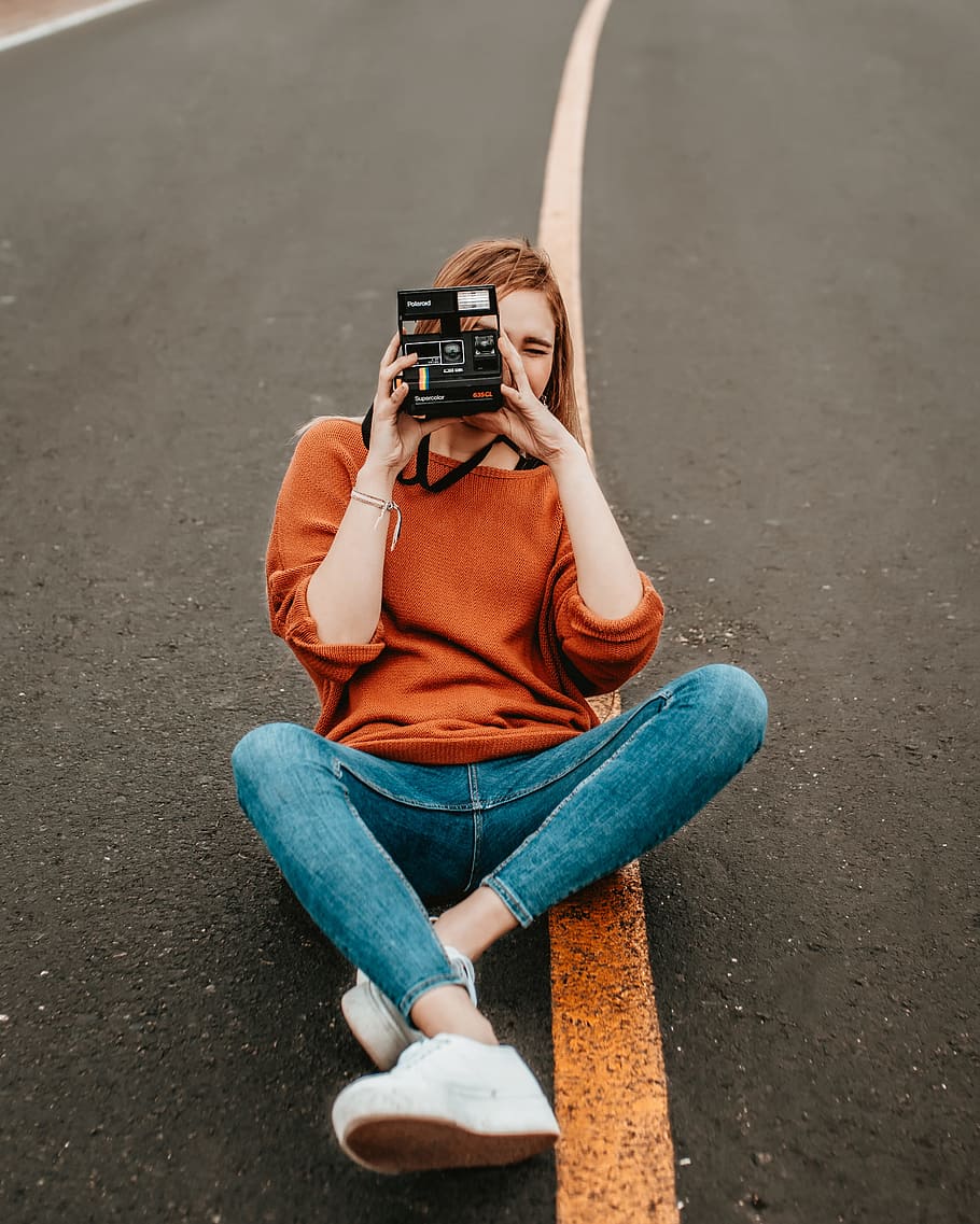 woman sitting at the middle of the road with one step camera during daytime HD wallpaper