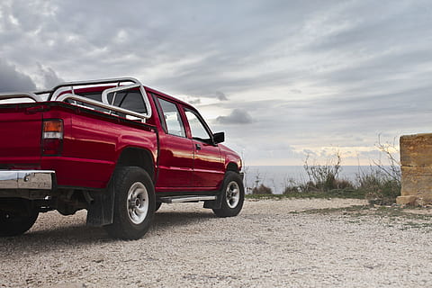 A red pick-up truck parked by the sea in an overcast weather HD wallpaper