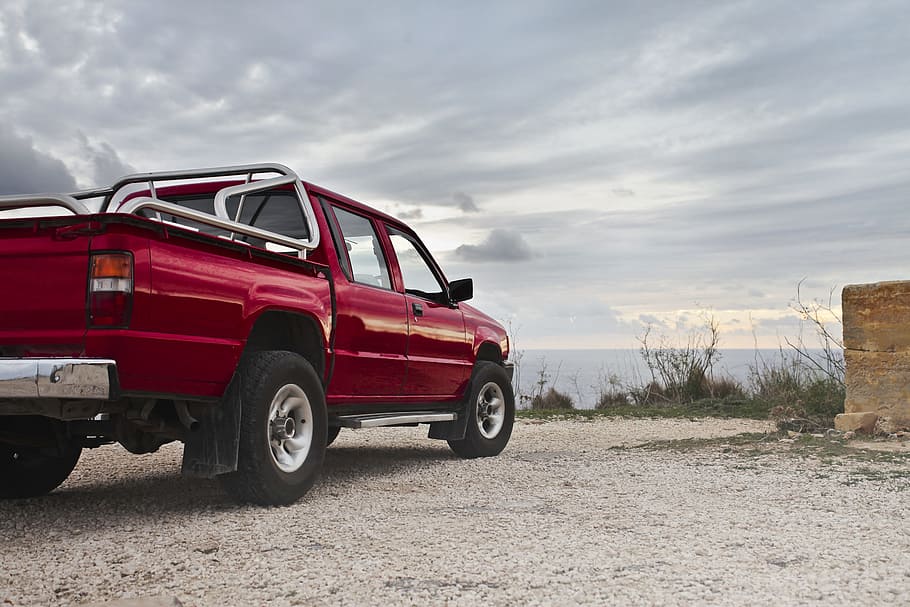 A red pick-up truck parked by the sea in an overcast weather HD wallpaper