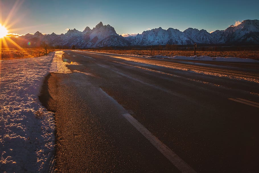 empty road near ice-capped mountains during golden hour, asphalt
