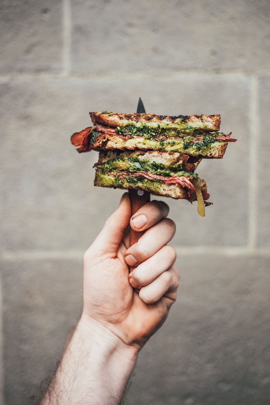 Gourmet pesto sandwich held with knife in a hand, barbecue, bread
