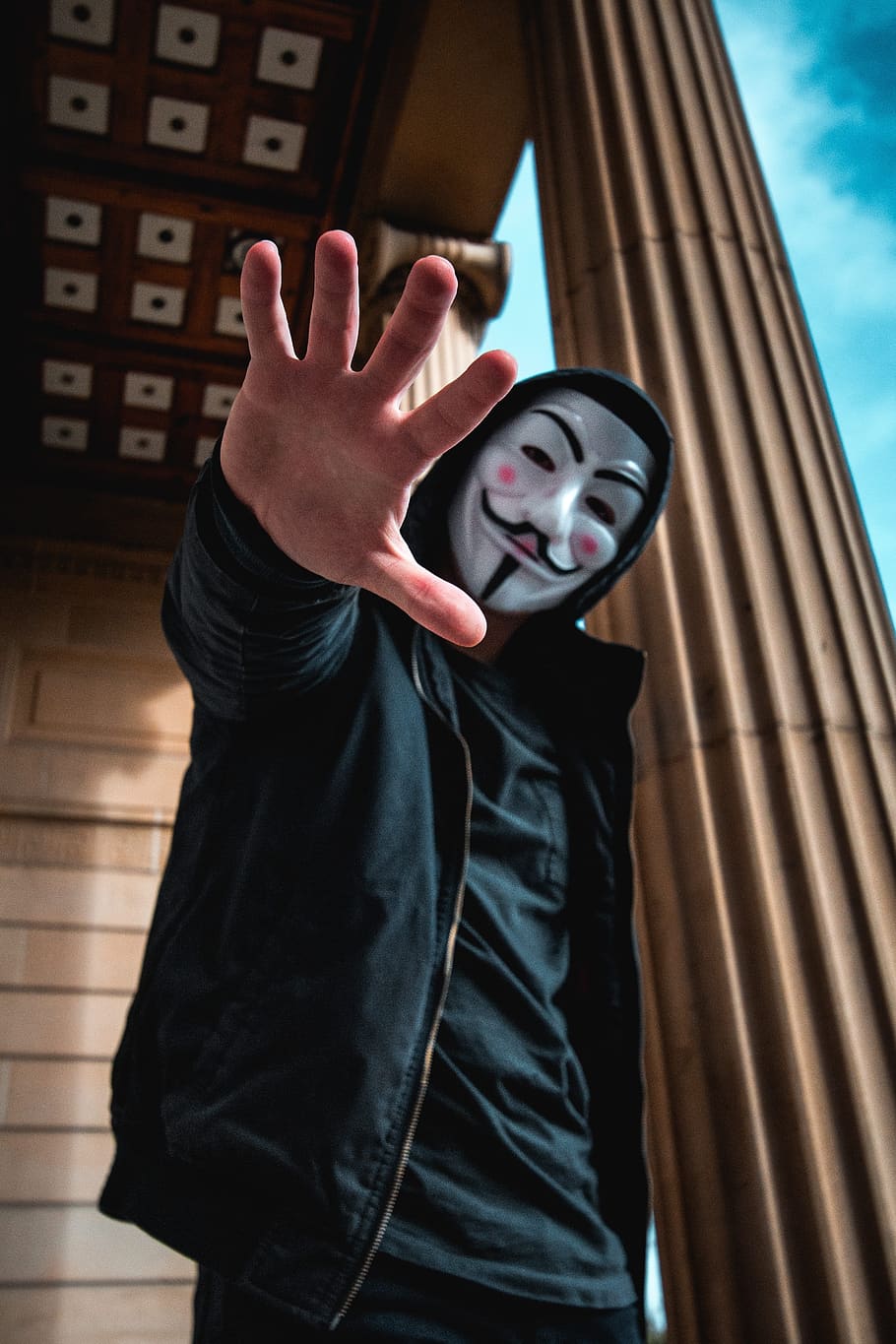 man wearing Guy Fawkes Mask standing inside building, person