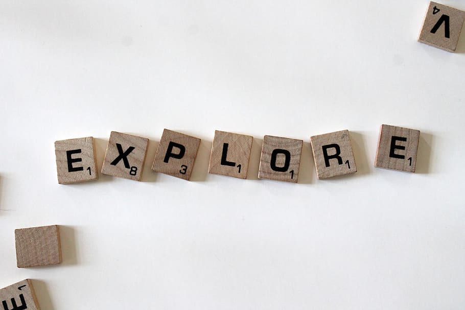 flat lay photography of scrabble tiles forming explore word, text