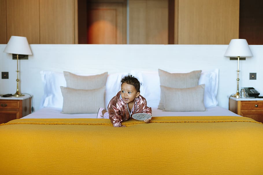 baby in pink jacket on yellow bed, hotel, kingsize, infant, toddler, HD wallpaper