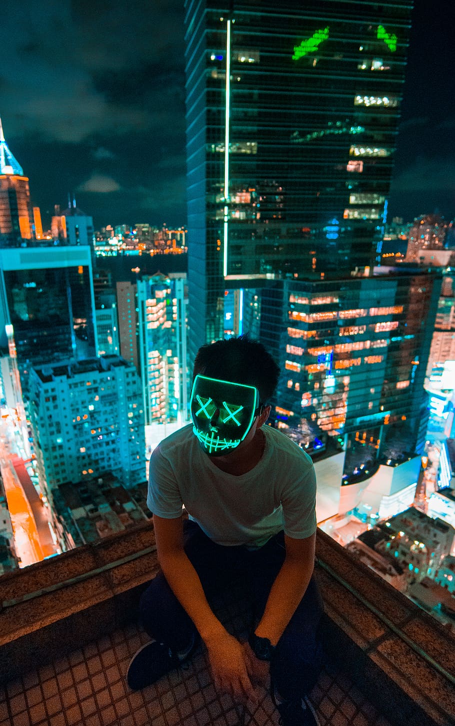 man wearing mask sitting on top of building, person, human, people