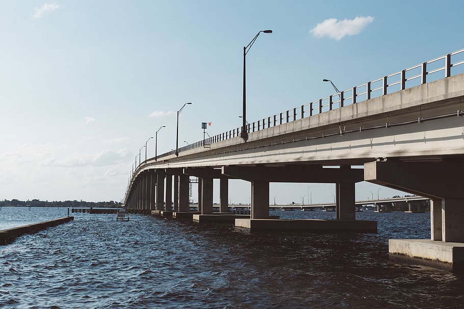 Brown Concrete Bridge Above Body of Water Under Blue Sky and White Clouds HD wallpaper