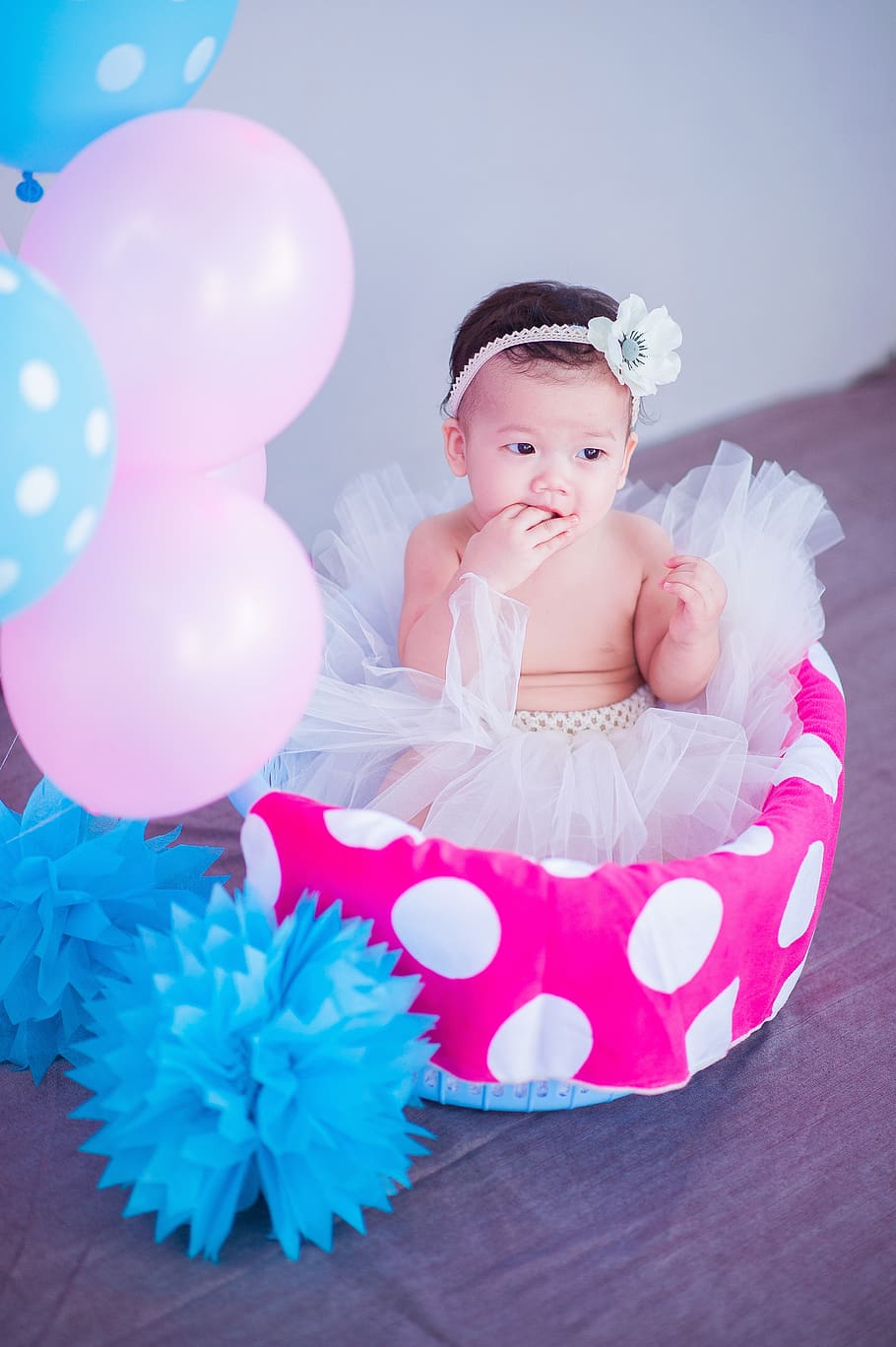 Baby Sitting on White and Pink Polka-dot Basket With Balloons