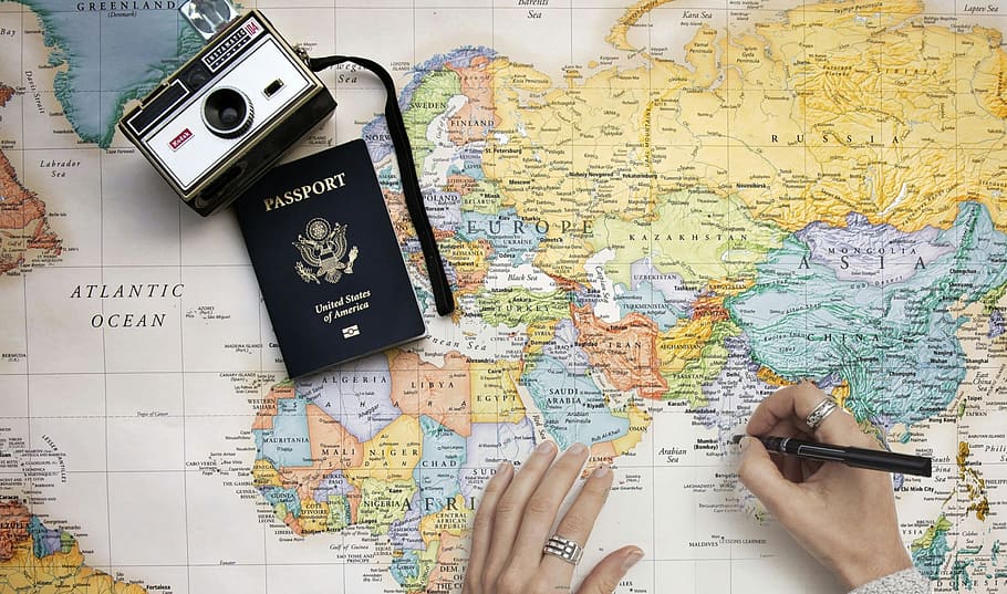 Concept photo with world travel theme. Person planning trip with world man, camera and passport.