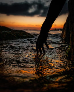 Silhouette of Person's Hand Touching Water during Sunset, backlit HD wallpaper
