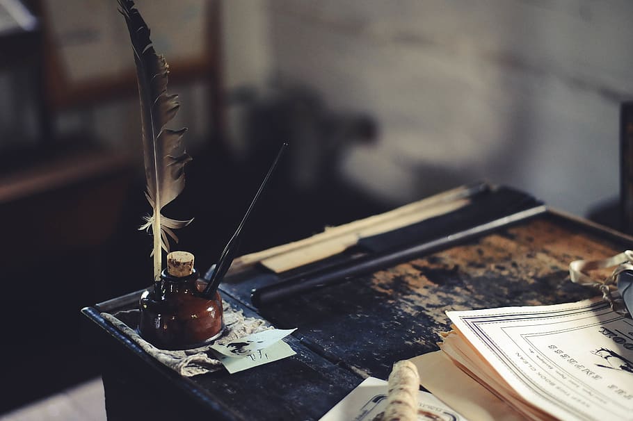 ink bottle on desk, focus on foreground, no people, quill pen