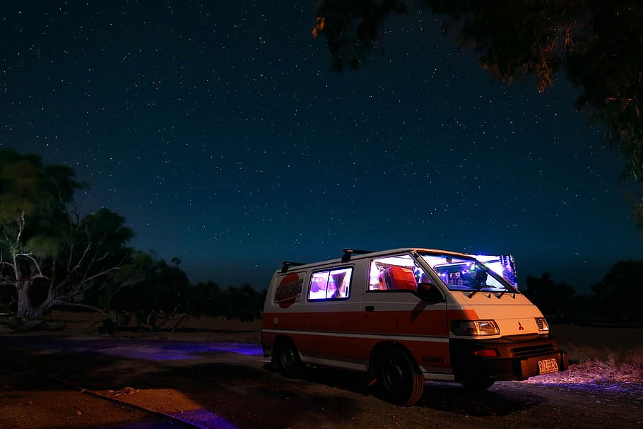 white Mitsubishi L300 parked near tree under starry sky, camping