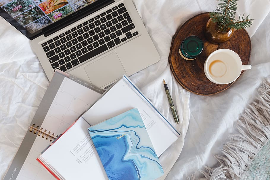 Bed full of pillows and notebooks with Apple gadgets, magazines HD wallpaper