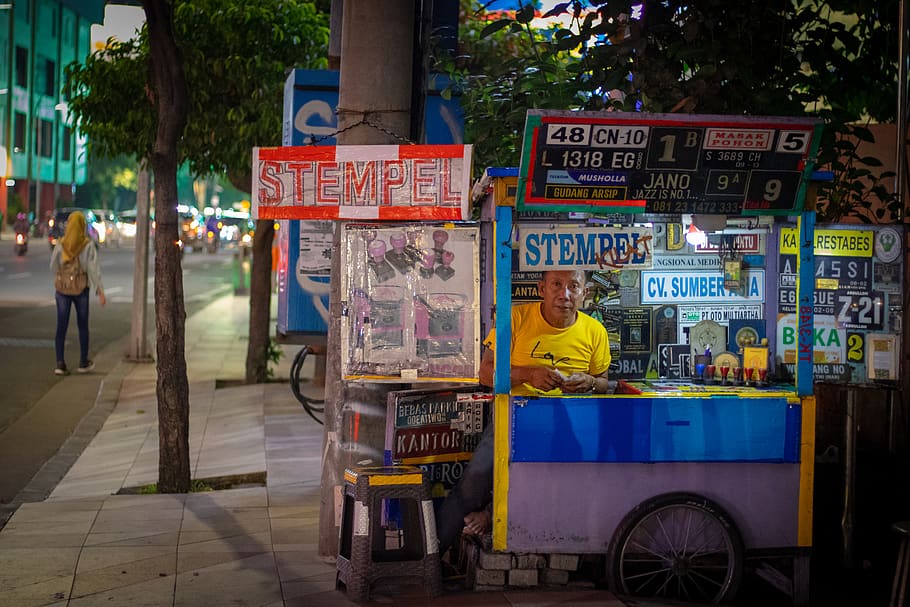 man sitting inside the store, person, human, kiosk, wheel, machine HD wallpaper
