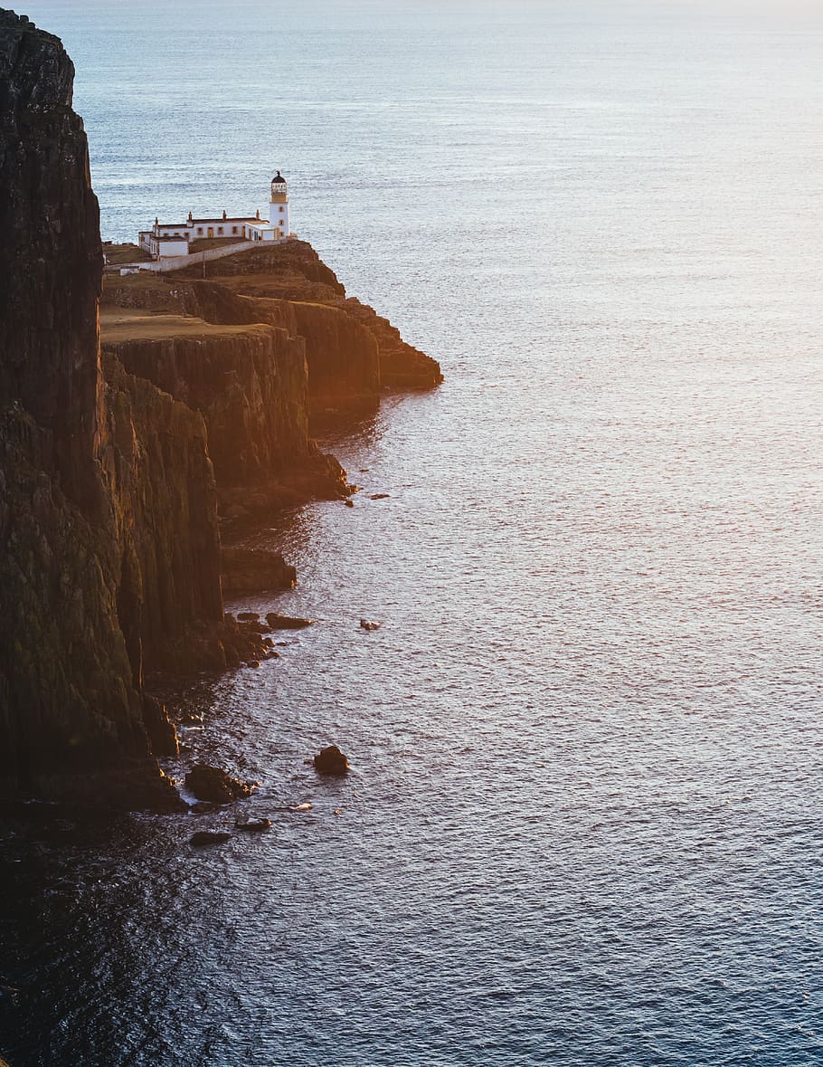 white lighthouse on hill near body of water, outdoors, nature