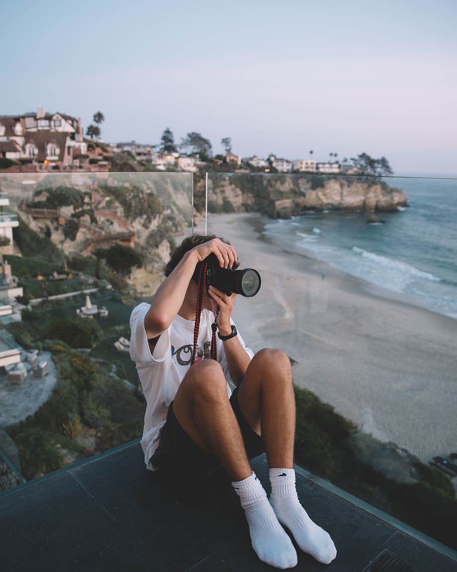 person using DSLR camera sitting near the cliff, ocean view, canon HD wallpaper