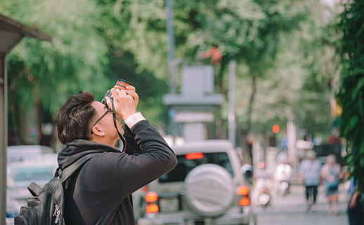 Man Wearing Black Hoodie Holding Dslr Camera Shooting on Upper Direction HD wallpaper