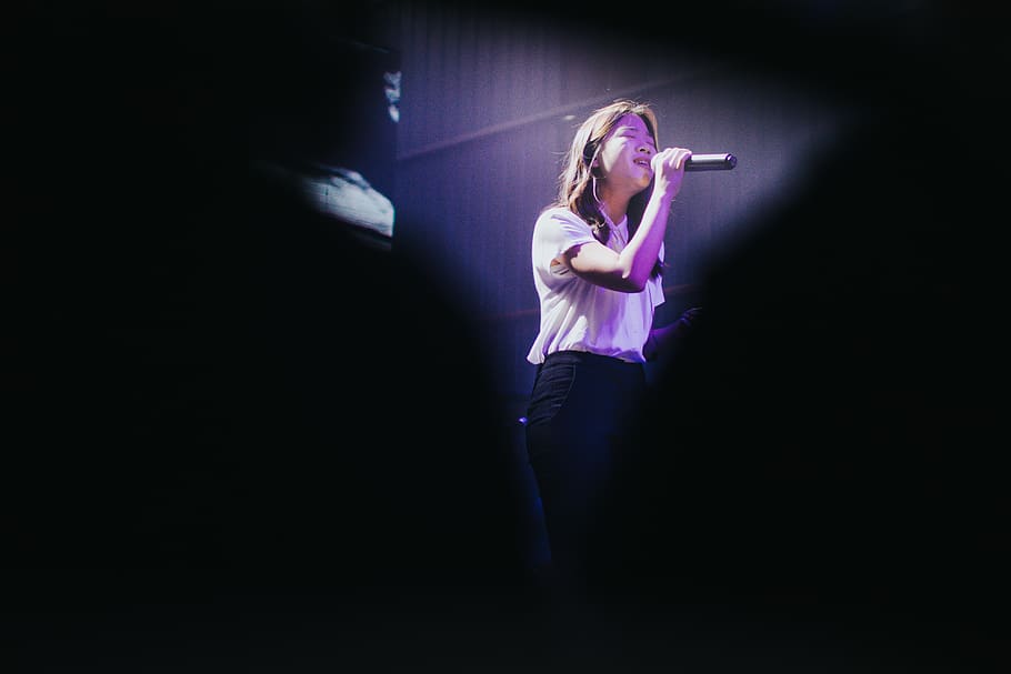 woman wearing white shirt singing inside room, lighting, person