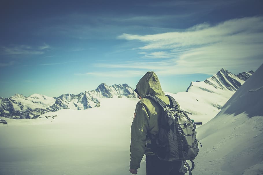 Person Wearing Green Jacket Walking on White Snow Covered Mountain HD wallpaper
