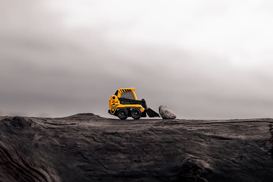 yellow skid steer loader in front of stone, mode of transportation