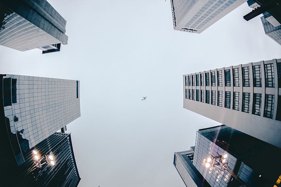 Low Angle Photography of Airplane Flying Above High Rise Buildings HD wallpaper