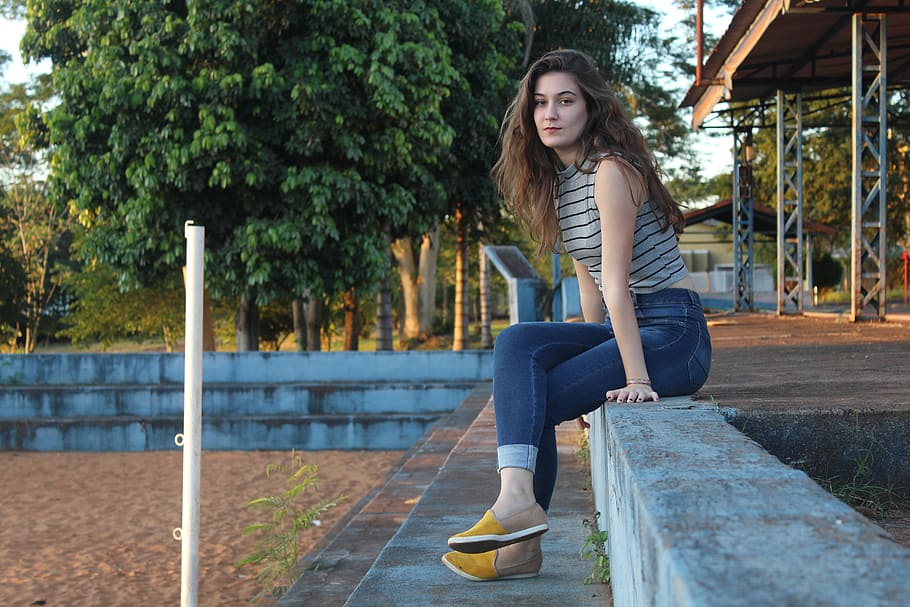 woman sitting on concrete surface during daytime, apparel, clothing