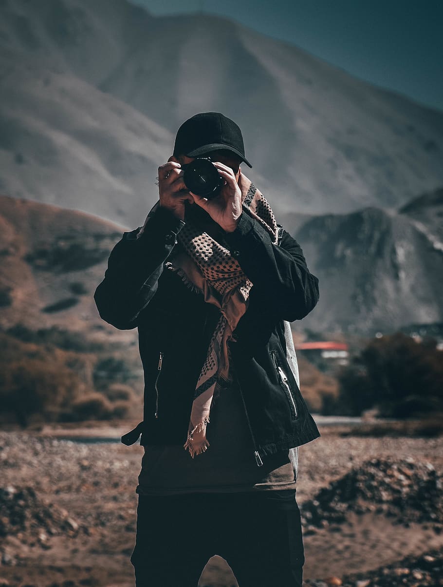 Person Holding Camera, blurred background, cap, daylight, landscape HD wallpaper
