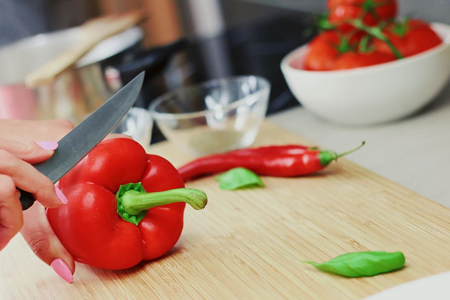 Person Slicing Red Chili Pepper on Brown Wooden Chopping Board HD wallpaper