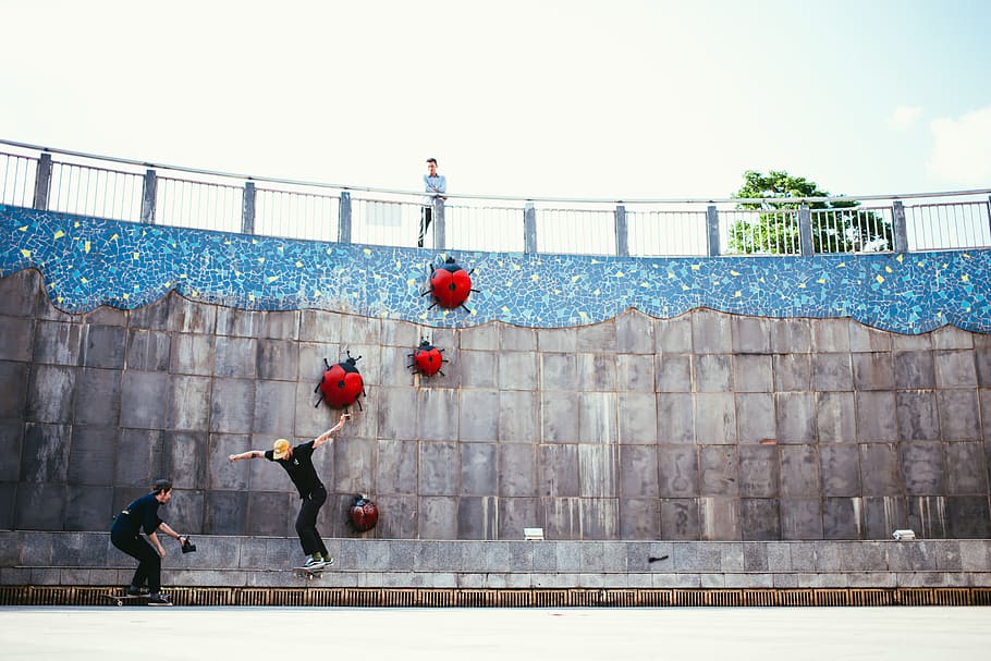An onlooker watching one skateboarder being photographed by another in a skatepark HD wallpaper