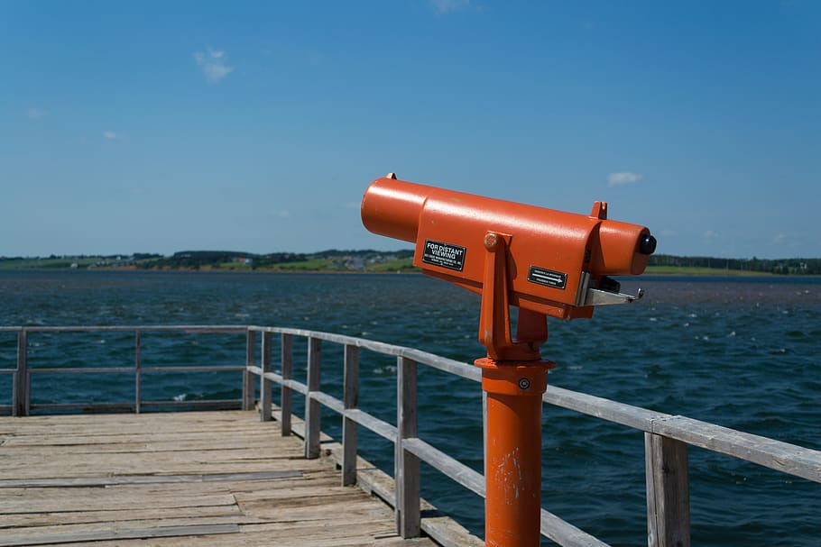 orange telescope on seadock, railing, handrail, banister, waterfront