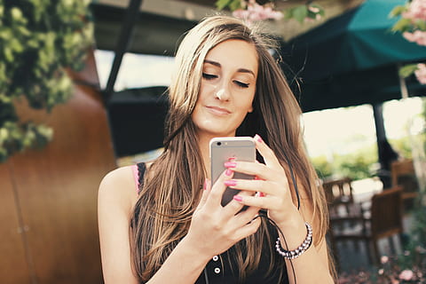 A young girl uses an app for a chat on a smartphone outdoors HD wallpaper