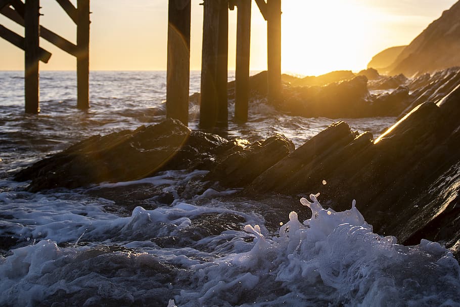 Seawaves and Boulders Under Dockyard during Golden Hour, dawn HD wallpaper