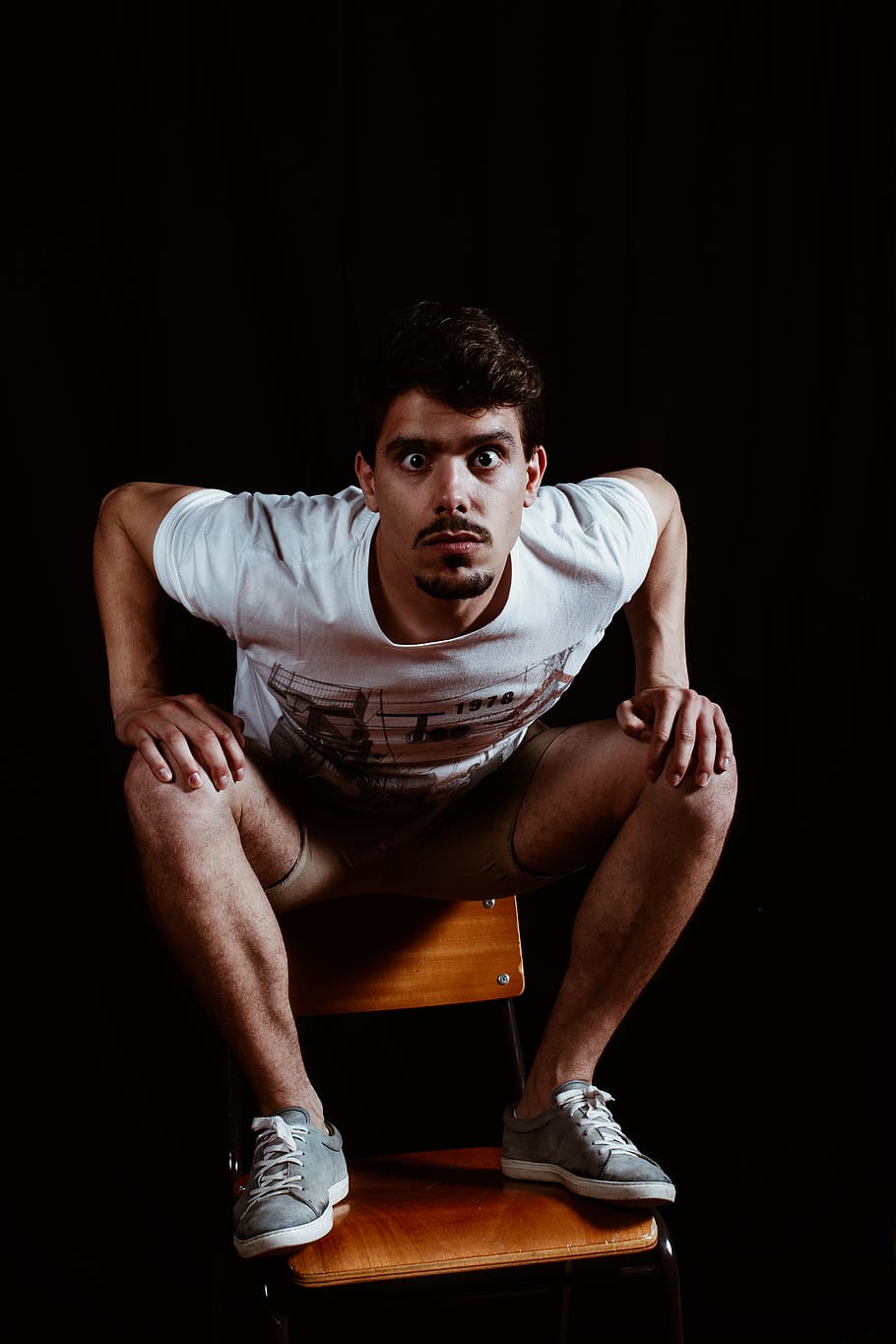 Man Wearing White Crew-neck Short-sleeved Shirt Sitting on Brown Wooden Chair HD wallpaper